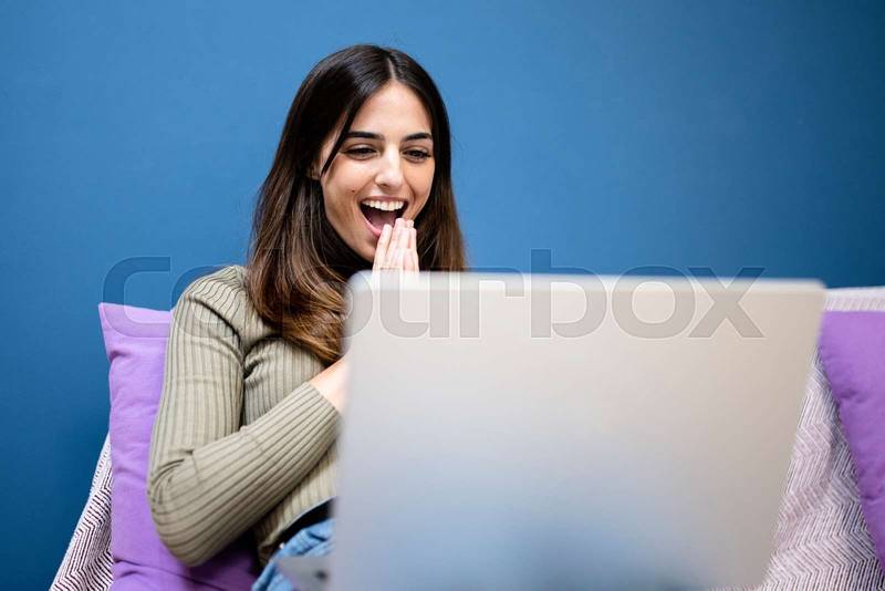 excited beautiful woman looking at laptop - happy laughing girl reading an email