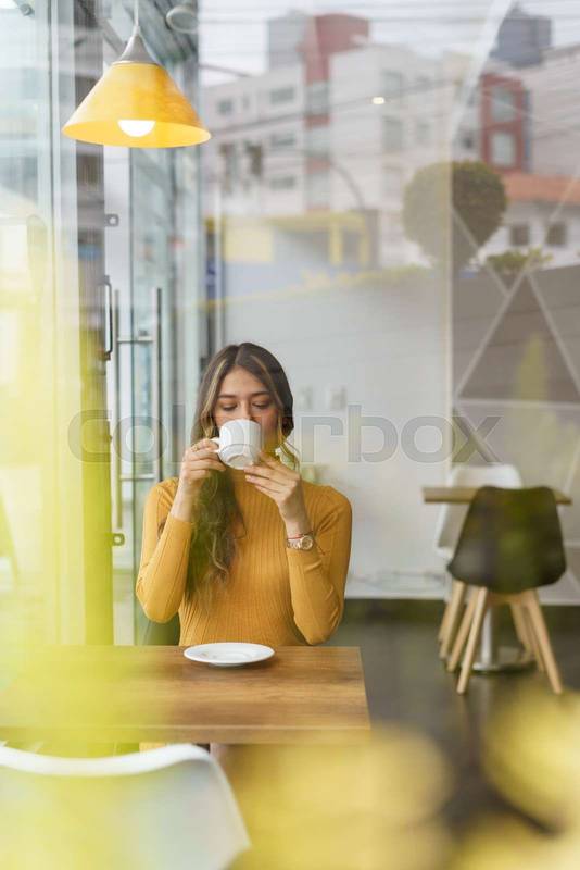 woman with long blonde hair sitting enjoying and having a cup of hot drink, lifestyle