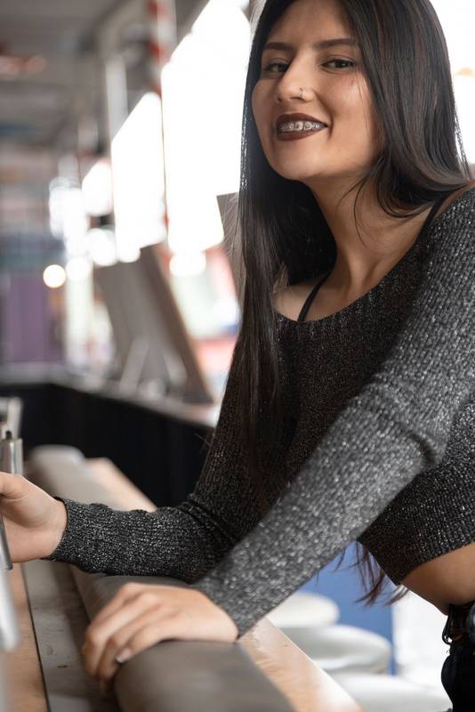 beautiful cheerful Latin woman leaning against a bar
