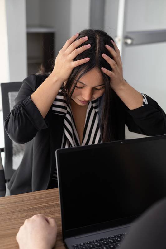 young professional faces intense pressure, head in hands, as workplace stress