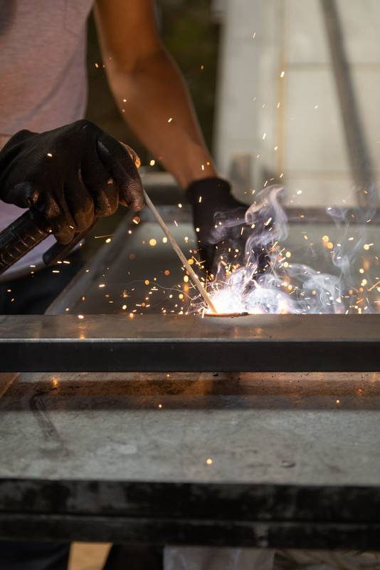 wearing protective gloves while using a metal welding tool, sparks from the machine