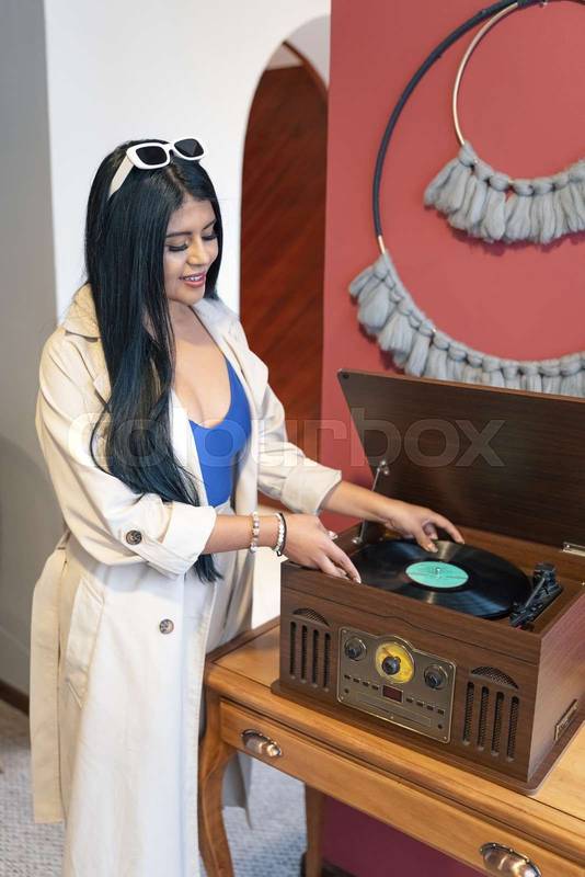 woman using vintage turntable with record, playing music