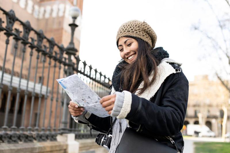 happy traveller woman looking a map outdoors. cheerful young female on vacations.