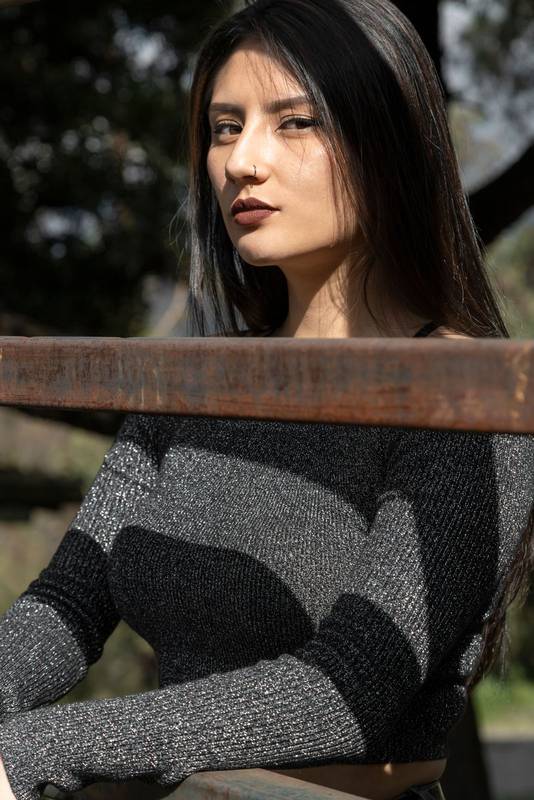 woman with long black hair behind a wood, relaxed on a summer day in the countryside