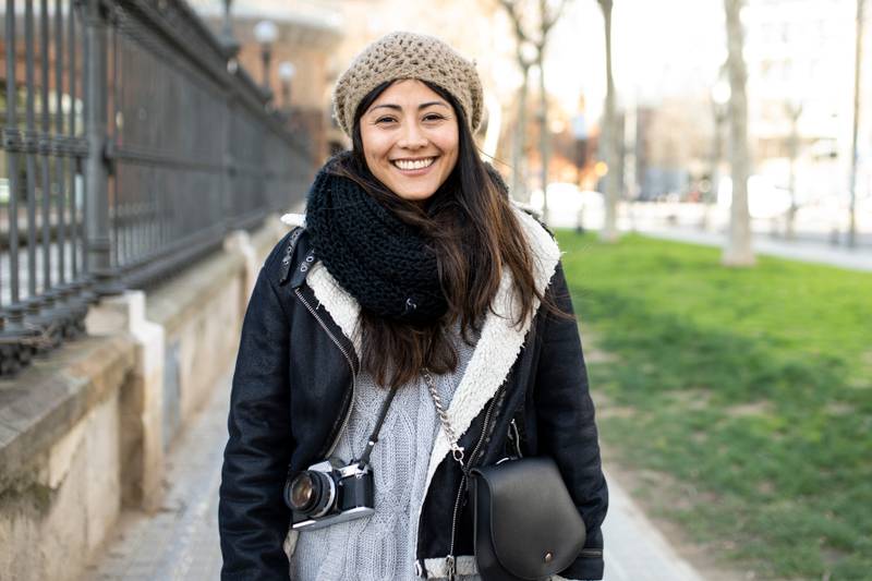 portrait of happy woman with camera in the city during her holidays. Travel, tourist concept