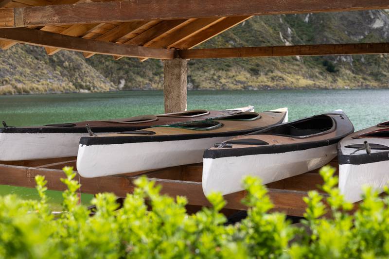 kayaks rests under a wooden shelter by the lake, surrounded by mountains