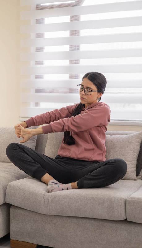 peaceful woman stretches with arms lifted above her head on a soft beige sofa, enjoying a quiet