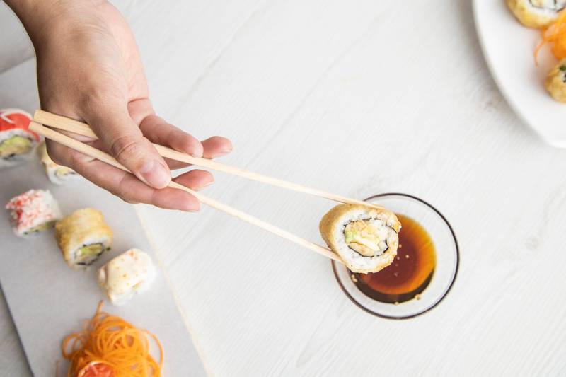 restaurant sushi roll with wooden chopsticks, at the bottom is a container with sauce