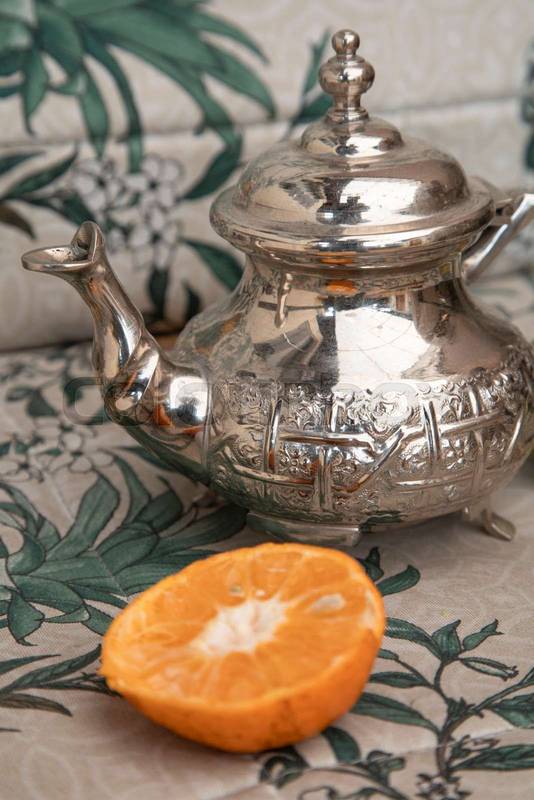 kitchen objects traditional metal teapot next to an orange slice