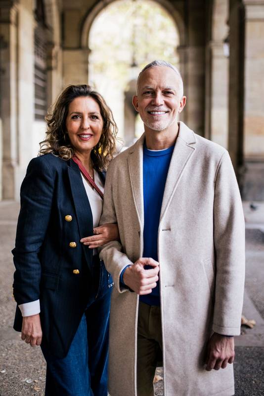 Affectionate senior man and woman standing happy and relaxed in old town. Mature couple bonding together in looking at camera and holding arms.