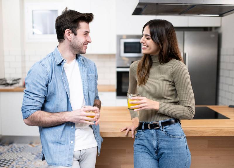 lovely young couple sitting on the kitchen table. Two cheerful young guys smiling at home. love, friendly and confident concept