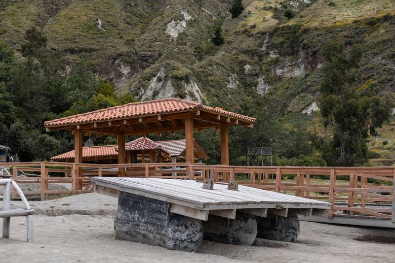 charming cabin stands behind a rustic stone picnic table surrounded by lush greenery