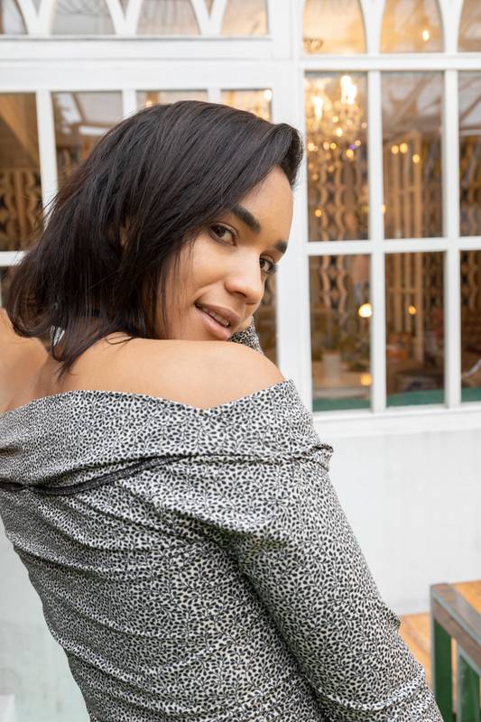 woman with short hair smiling looking at the camera showing her back and shoulder