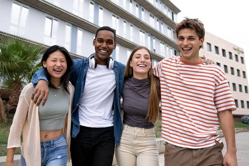 Happy multiracial group of friends having fun looking at camera.Diverse cheerful young people laughing standing outside.