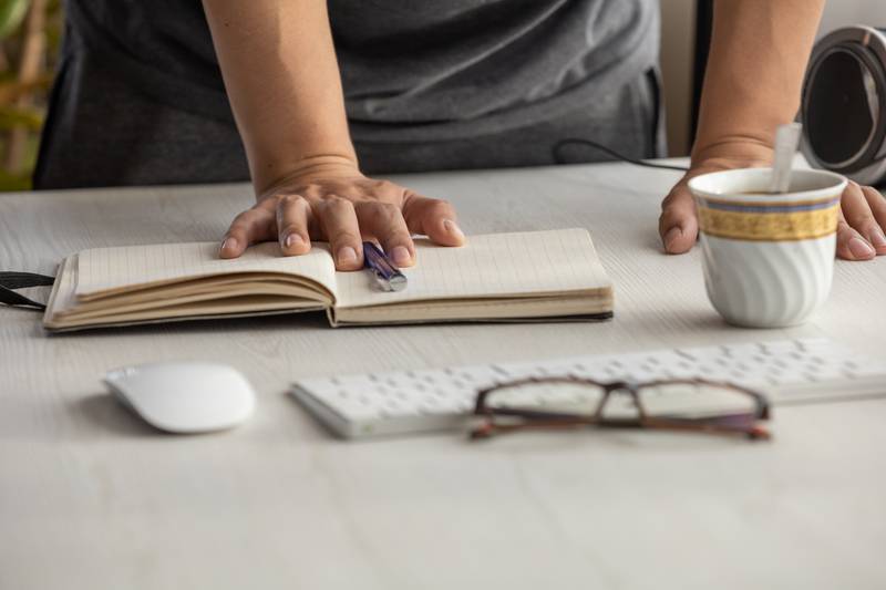 open and empty notebook, desk with glasses, pen, cup of coffee