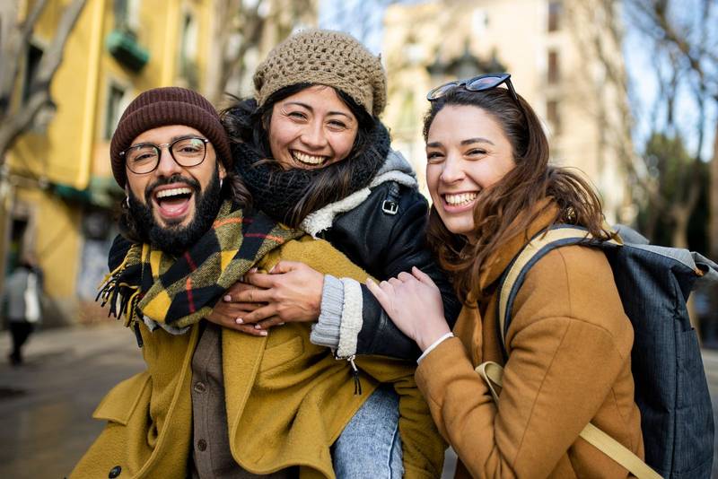 three happy young friends having fun in the city. Multiracial group smiling and looking at camera. Travel concept