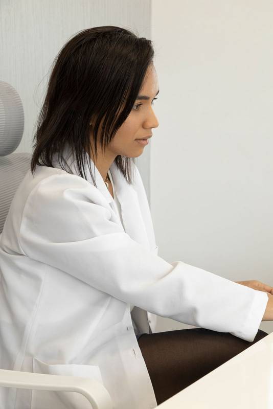 latin doctor with short hair sitting at her office desk,