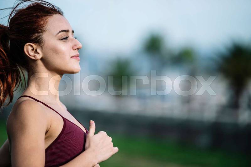 Close up of active sport fitness woman jogging outside. Female young adult athlete running training cardio for a marathon.