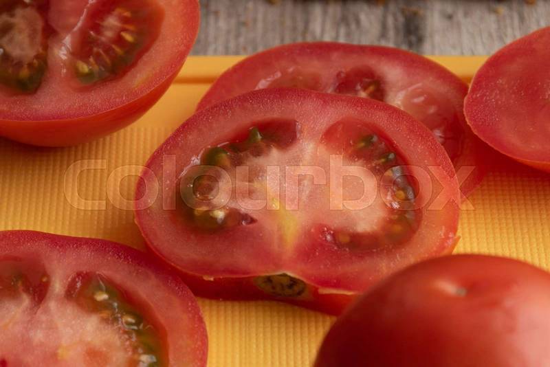 fresh tomato slices with its seeds on a chopping board, vegetable